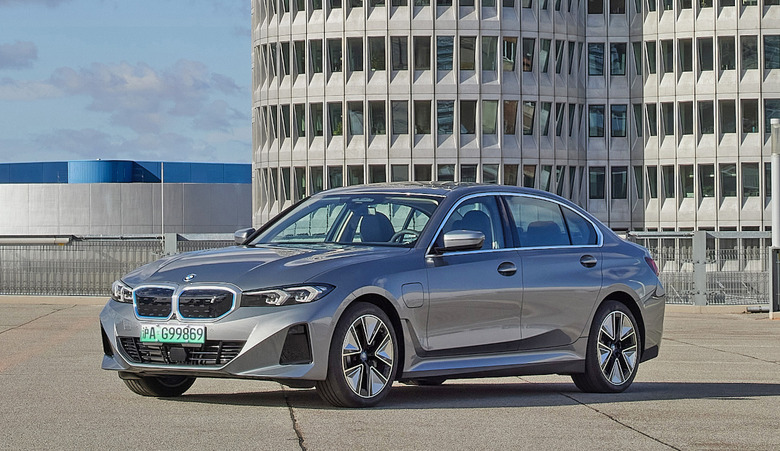The BMW i3 parked on the roof level of a parking garage with high-rise buildings in the background.
