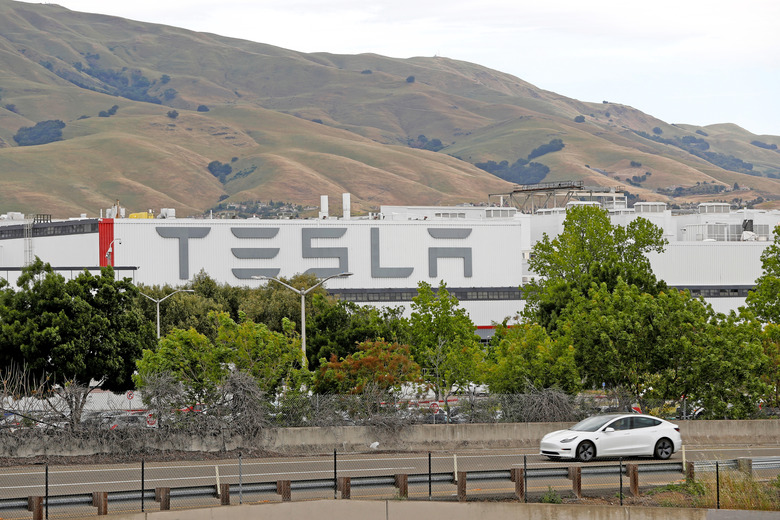 A Tesla vehicle drives past Tesla's primary vehicle factory after CEO Elon Musk announced he was defying local officials' coronavirus disease (COVID-19) restrictions by reopening the plant in Fremont, California, U.S. May 11, 2020. REUTERS/Stephen Lam