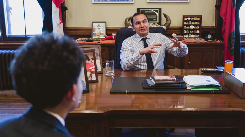 Canada's premier for Manitoba, Wab Kinew, chatting with someone in an office.