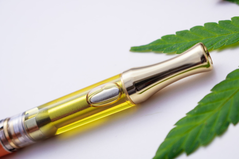 Full gram cartridge with cannabis oil and terpenes inside. With weed leaf on white background. An alternative method of smoking medical marijuana.