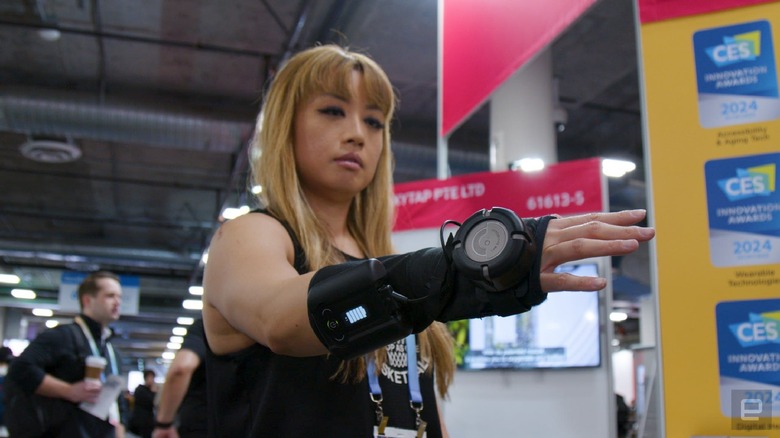 A woman wearing the GyroGlove at the CES 2024, holding her hand out.