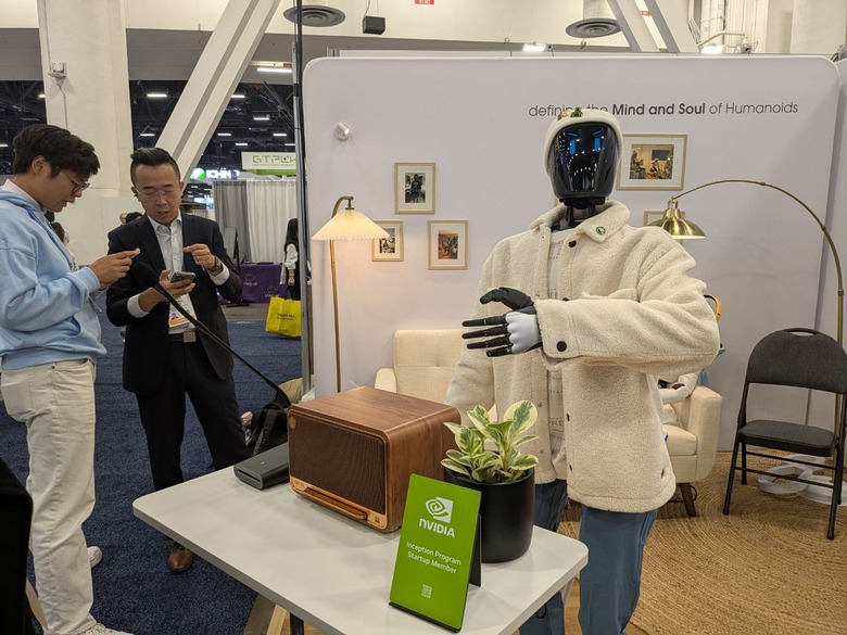 A humanoid robot wearing a beanie and a jacket standing at a booth at CES 2026.