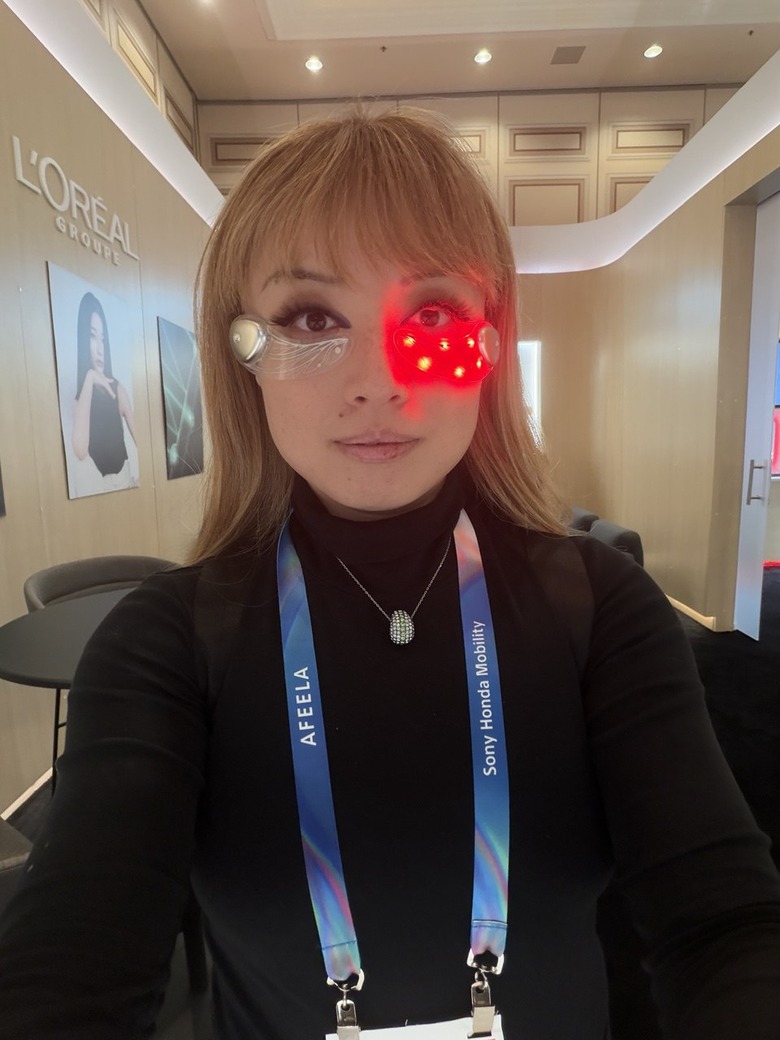 A person with the Loreal LED Eye masks on, with the one under her left eye turned on. It's glowing red.