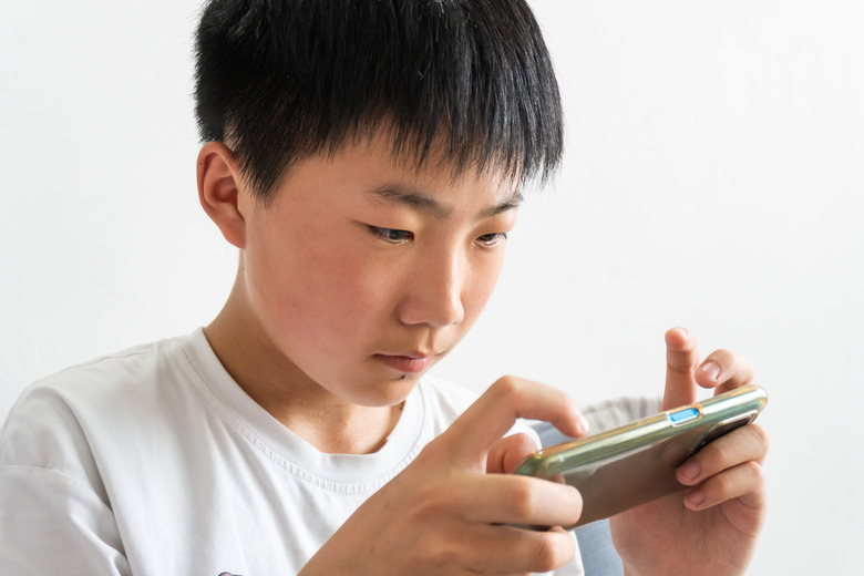 Asian boy playing mobile game on his smartphone