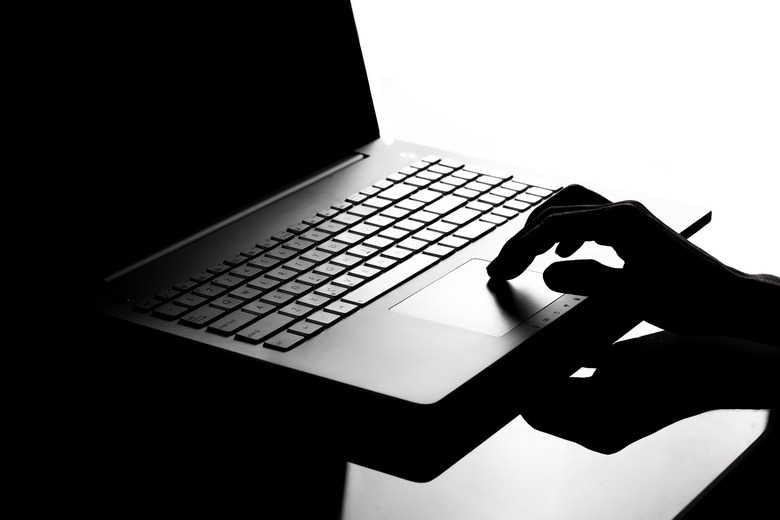 Close-Up Of Silhouette Hand Using Laptop At Table