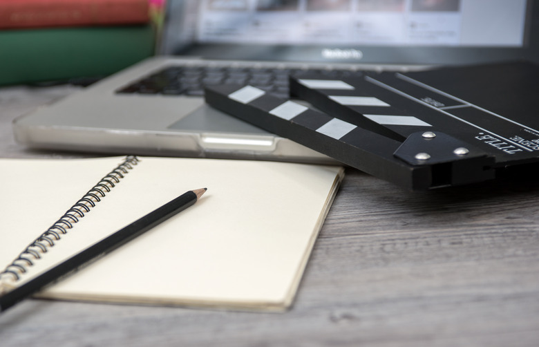 office stuff with Movie clapper laptop and coffee cup pen notepad on the wood table top view shot.dark effect