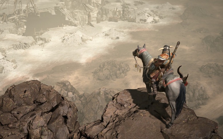 A Diablo IV barbarian on his mount, overlooking a deserted mine in rocky desert. 
