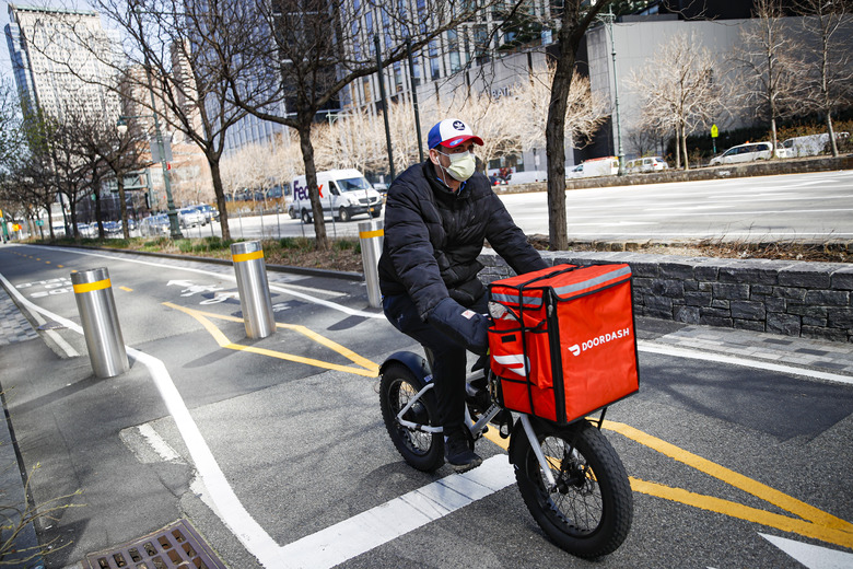 FILE - In this March 16, 2020 file photo, a delivery worker rides his bicycle along a path on the West Side Highway in New York. New York City was ordered Friday, July 7, 2023, to temporarily delay new minimum pay standards for food delivery workers after being sued by Uber Eats, DoorDash and Grubhub. (AP Photo/John Minchillo, File)
