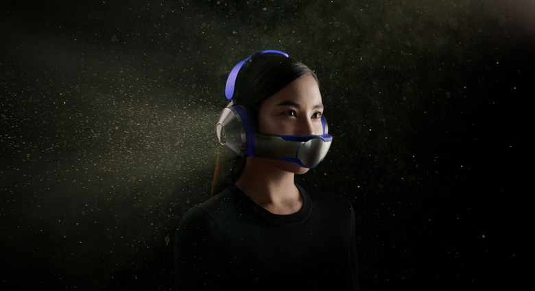 A person wearing the Dyson Zone headphone and mask combo, with a purple headband and silver/grey earcups. The graphic shows what look like dust particles surrounding the headphones.