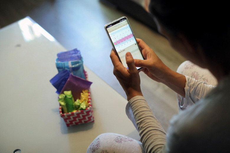 Raquel del Rio, 36, who works in police forces, poses as she observes a period calendar tracker app on her mobile phone at her home in Madrid, Spain, May 16, 2022. Picture taken May 16, 2022. REUTERS/Isabel Infantes