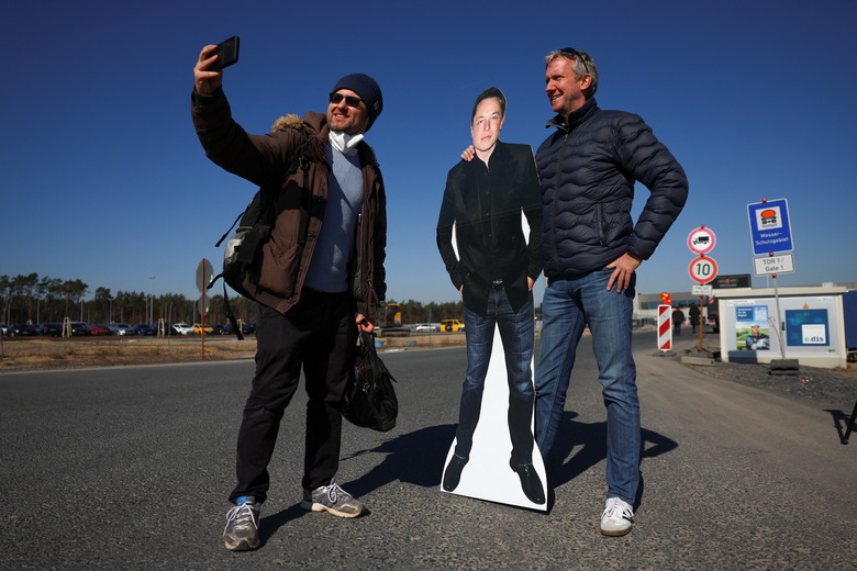 Tesla fan Martin Wrobel poses with a man and a paper figure of Elon Musk outside the new Tesla Gigafactory for electric cars in Gruenheide, Germany, March 22, 2022. REUTERS/Lisi Niesner