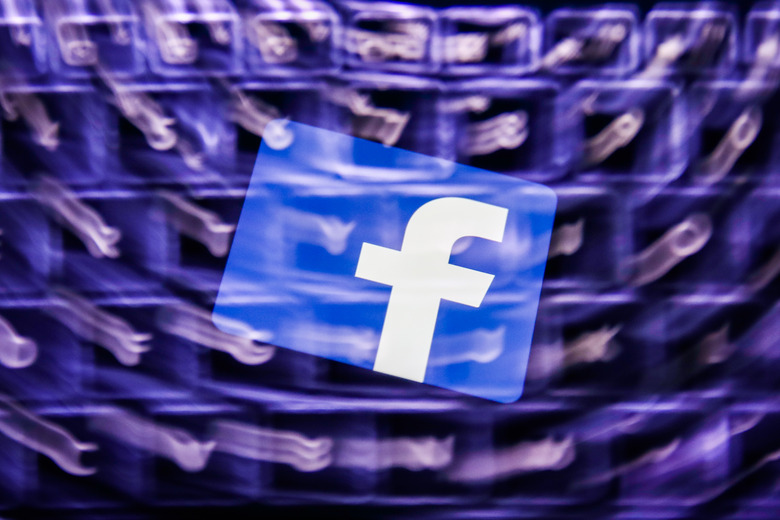 Facebook logo displayed on a phone screen and a keyboard are seen in this multiple exposure illustration photo taken in Poland on February 8, 2021. Facebook reacted negatively to Apple's privacy policy changes. (Photo illustration by Jakub Porzycki/NurPhoto via Getty Images)