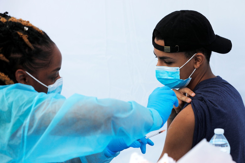 A teenage student receives a dose of the Pfizer-BioNTech vaccine for the coronavirus disease (COVID-19) during a vaccination event for local adolescents and adults outside the Bronx Writing Academy school in the Bronx borough of New York City, New York, U.S., June 4, 2021. REUTERS/Mike Segar