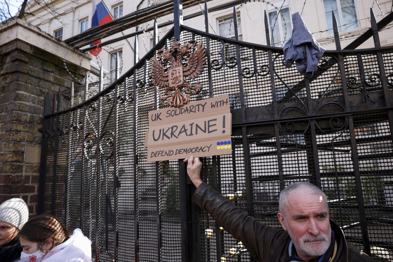A protestor holds a sign in front of the gate of the Russian Embassy during an anti-war protest, after Russia launched a massive military operation against Ukraine, in London, Britain, February 26, 2022. REUTERS/Henry Nicholls