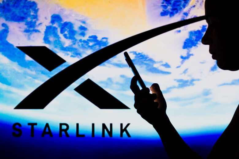 BRAZIL - 2022/05/02: In this photo illustration, the Starlink logo is seen in the background of a silhouetted woman holding a mobile phone. (Photo Illustration by Rafael Henrique/SOPA Images/LightRocket via Getty Images)