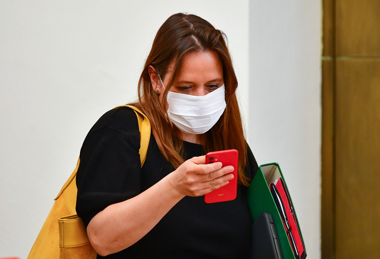 13 May 2020, Brandenburg, Potsdam: Manja Schüle (SPD), Brandenburg Minister of Science, Research and Culture, put on a mouth and nose protector during the session of the Brandenburg state parliament. Because of the danger of infection by corona, the seats of the members of parliament were protected with transparent walls made of Plexiglas. Photo: Soeren Stache/dpa-Zentralbild/ZB (Photo by Soeren Stache/picture alliance via Getty Images)