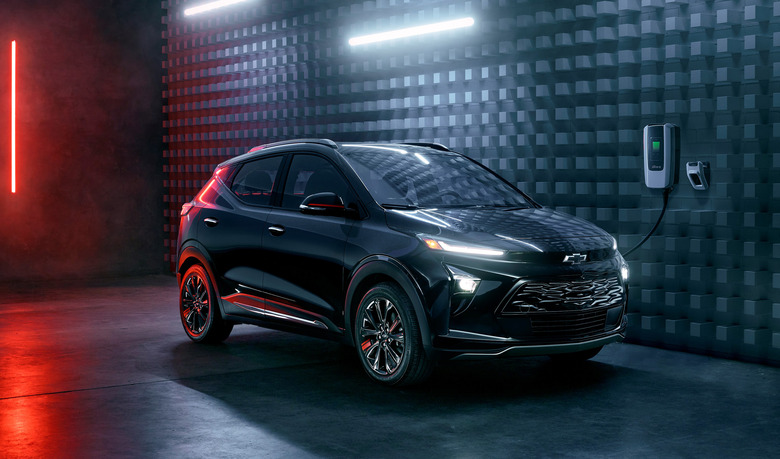 The 2023 Chevy Bolt charging in a modern black space with white and red neon highlights.