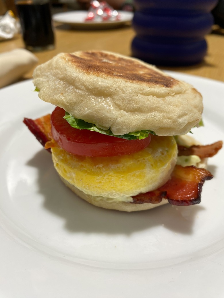 A breakfast sandwich with bacon, egg, tomato and a sad-looking piece of lettuce.