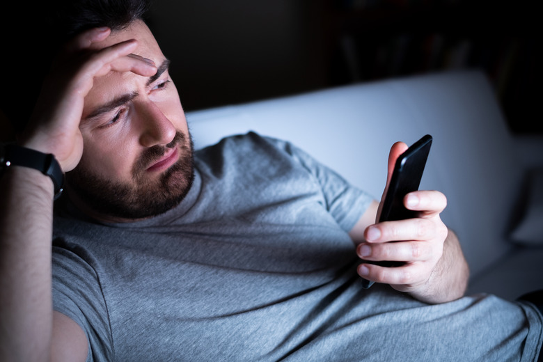 Sadness male portrait holding mobile phone alone