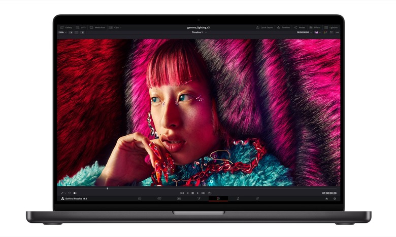 A press photo of the new Apple MacBook Pro powered by the new M3 chip. The dark gray laptop is facing forward with a photo of a young woman with brightly colored hair and a fuzzy blue top on the notebook's display.