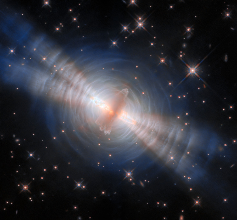 Hubble image of the Egg Nebula. A disc of gas and dust surrounded by beams of light and concentric rings of dust.
