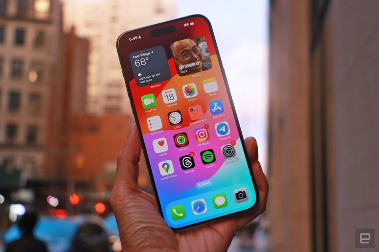 The iPhone 15 Pro Max held in mid-air in front of some New York City buildings.  