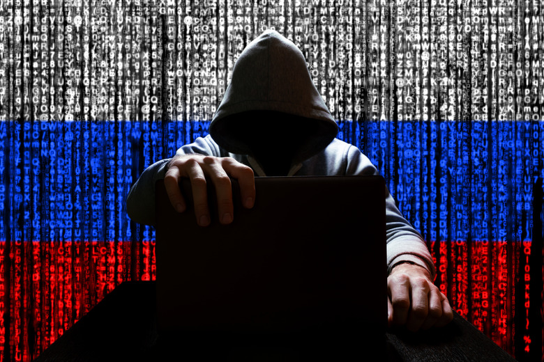 Russian hacker closes the lid of the laptop, against the backdrop of a binary code, the color of the Russian tricolor