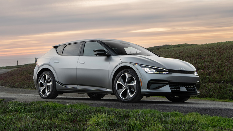 The Kia EV6 in grey riding on a country road near an oceanside cliff.