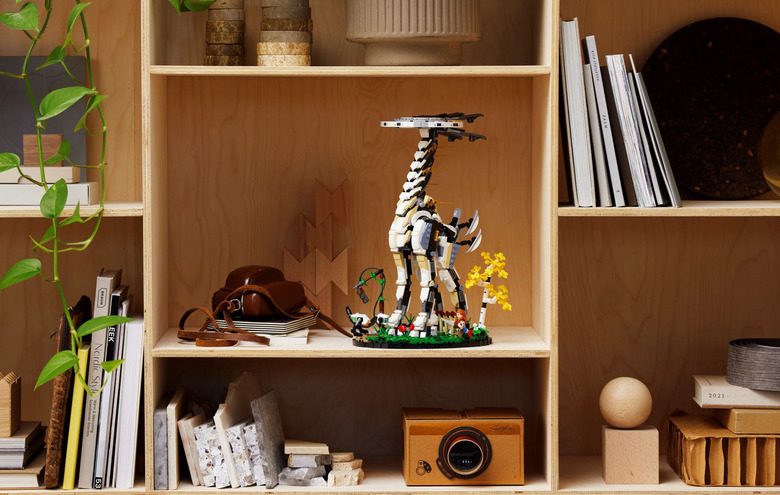 The new Horizon Forbidden West LEGO set with Tallneck seen placed on a shelf filled with books, a camera and other display items.