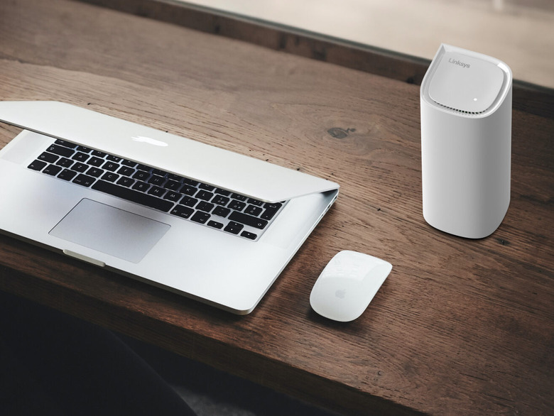 A router and a laptop on a desk.