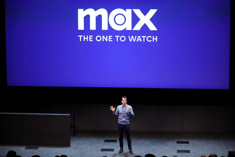 A person standing on a stage with the Max logo in the background.


