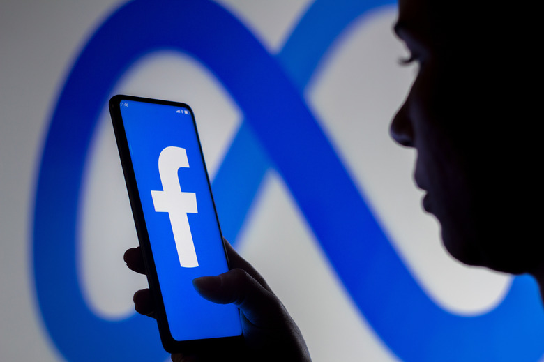 BRAZIL - 2022/03/16: In this photo illustration, a woman holds a smartphone with the Facebook logo displayed on the screen with the Meta Platforms logo displayed in the background. (Photo Illustration by Rafael Henrique/SOPA Images/LightRocket via Getty Images)