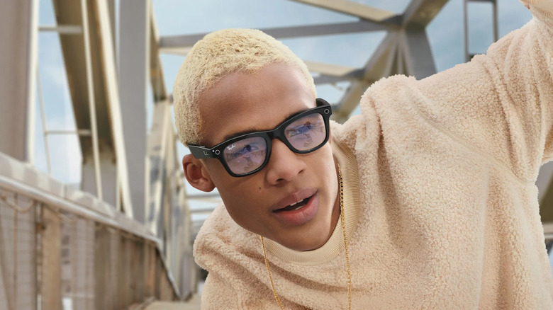 A promo photo of a person with cropped blonde hair wear Meta's Ray-Ban AR glasses.