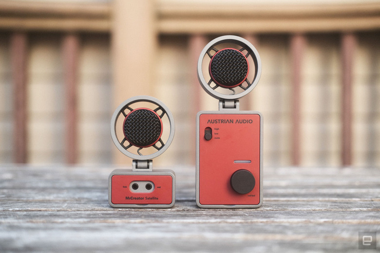 The Austrian Audio MiCreator in two parts: Two round microphones sit atop one smaller and one larger rectangular bases facing the camera and seen on a weathered wooden outdoor table.