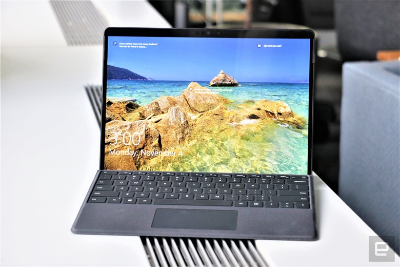 A photo of Microsoft Surface Pro X switched on with the sea as a wallpaper. The device is on top of a white table.