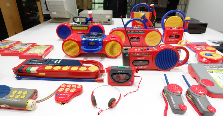 Array of My First Sony products on a table, including several tape players, walkie-talkies and a pair of headphones.