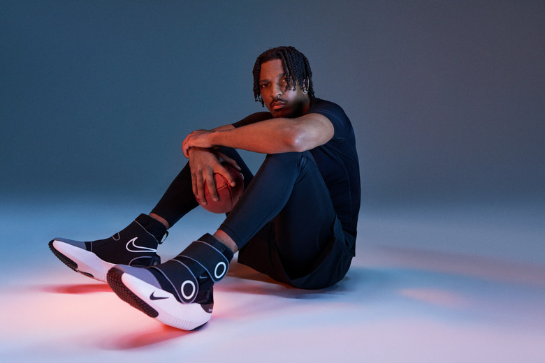 A person seated on the floor wearing big chunky footwear.