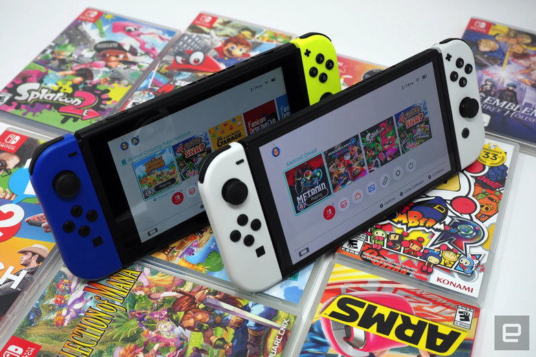 Nintendo Switch and Switch OLED sitting atop a collection of games.