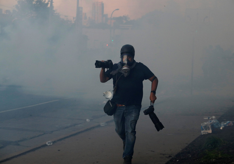 A photographer runs amid tear gas as demonstrations continue following the death in Minneapolis police custody of George Floyd, in Minneapolis, Minnesota, U.S. May 30, 2020. REUTERS/Carlos Barria