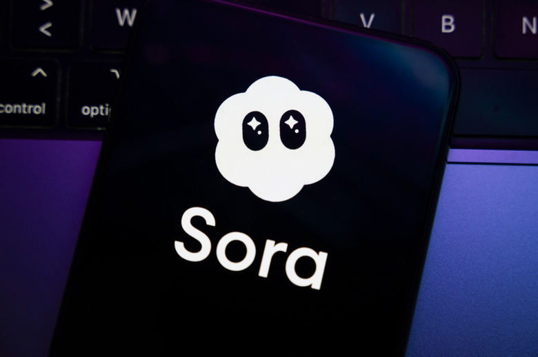 The Sora app logo appears on the screen of a smartphone placed on a computer keyboard illuminated by purple and blue light. OpenAI's top-ranked video creation and sharing app is controversial for its ability to create fake news and its disregard for copyright in Creteil, France, on October 9, 2025. (Photo by Samuel Boivin/NurPhoto via Getty Images)