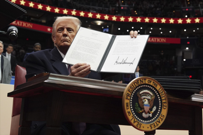President Donald Trump signs an executive order as he attends an indoor Presidential Inauguration parade event at Capital One Arena, Monday, Jan. 20, 2025, in Washington. (AP Photo/Evan Vucci)
