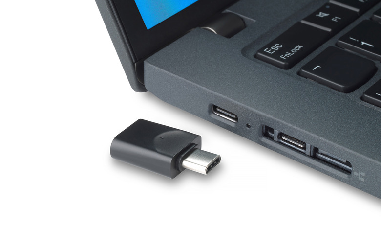 Marketing photo of a USB-C dongle sitting next to the side of a laptop