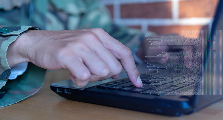 close up soldier man hand type command or check configuration on program software of security data with virtual code display laptop for military operation control system concept