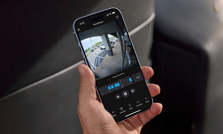 Image of a smartphone showing the Ring app with a 24/7 video feed on its display.