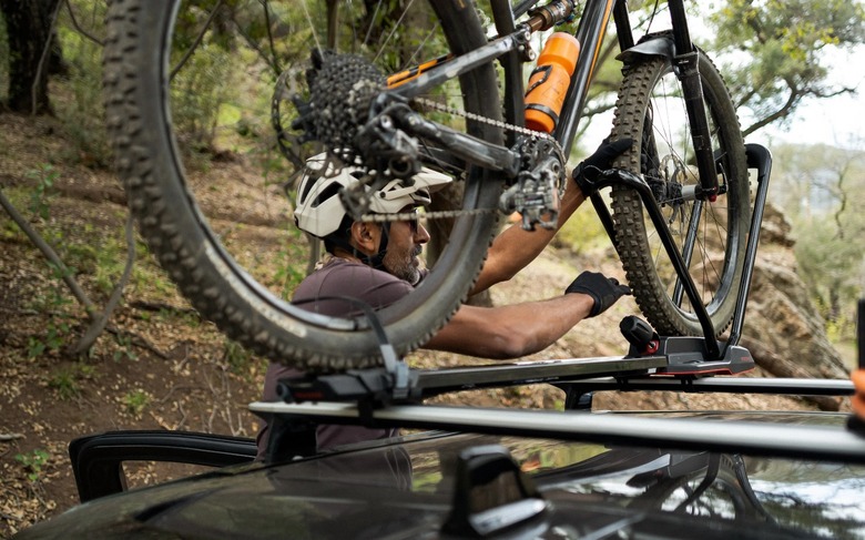 A photo of someone storing a mountain bike on top of a Rivian R1T truck. 