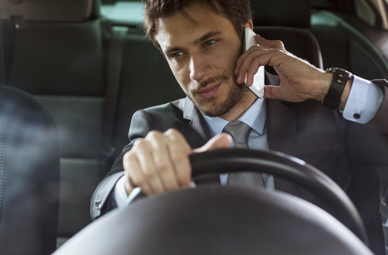 Close up of a handsome young businessman talking on mobile phone in his car