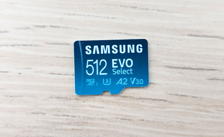 A closeup of a Samsung 512 EVO Select microSD card on a white wood-textured tabletop.