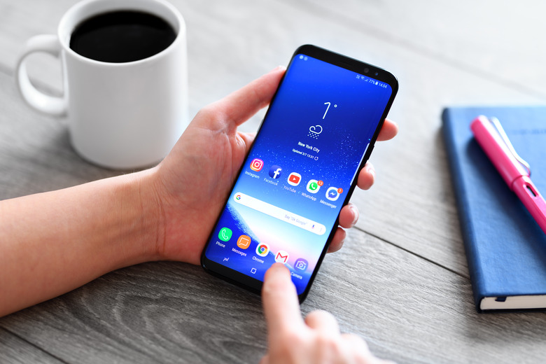 İstanbul, Turkey - March 7, 2017: Hand holding a smart phone on a wooden desk. The smart phone is an Samsung Galaxy S9 plus.  Samsung Galaxy is a touchscreen smart phone produced by Samsung Electronics.