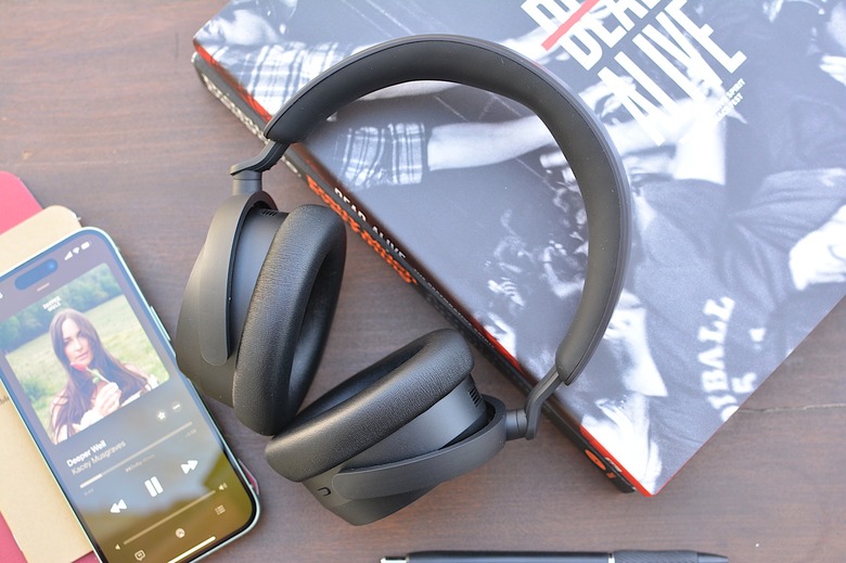 Sennheiser Accentum Plus headphones sitting on a table, propped up by two books with an iPhone playing Kacey Musgraves to the left.