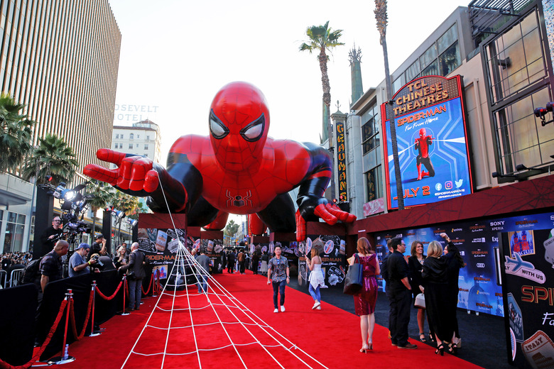 An inflatable spider-man hovers over the red carpet of a film premiere.